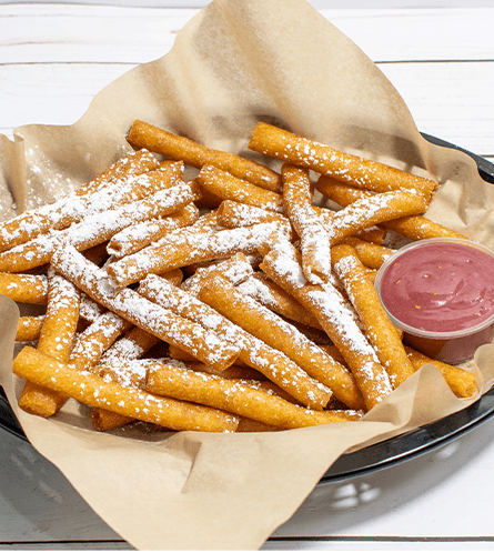 Sweet fried sticks with powdered sugar and berry dip