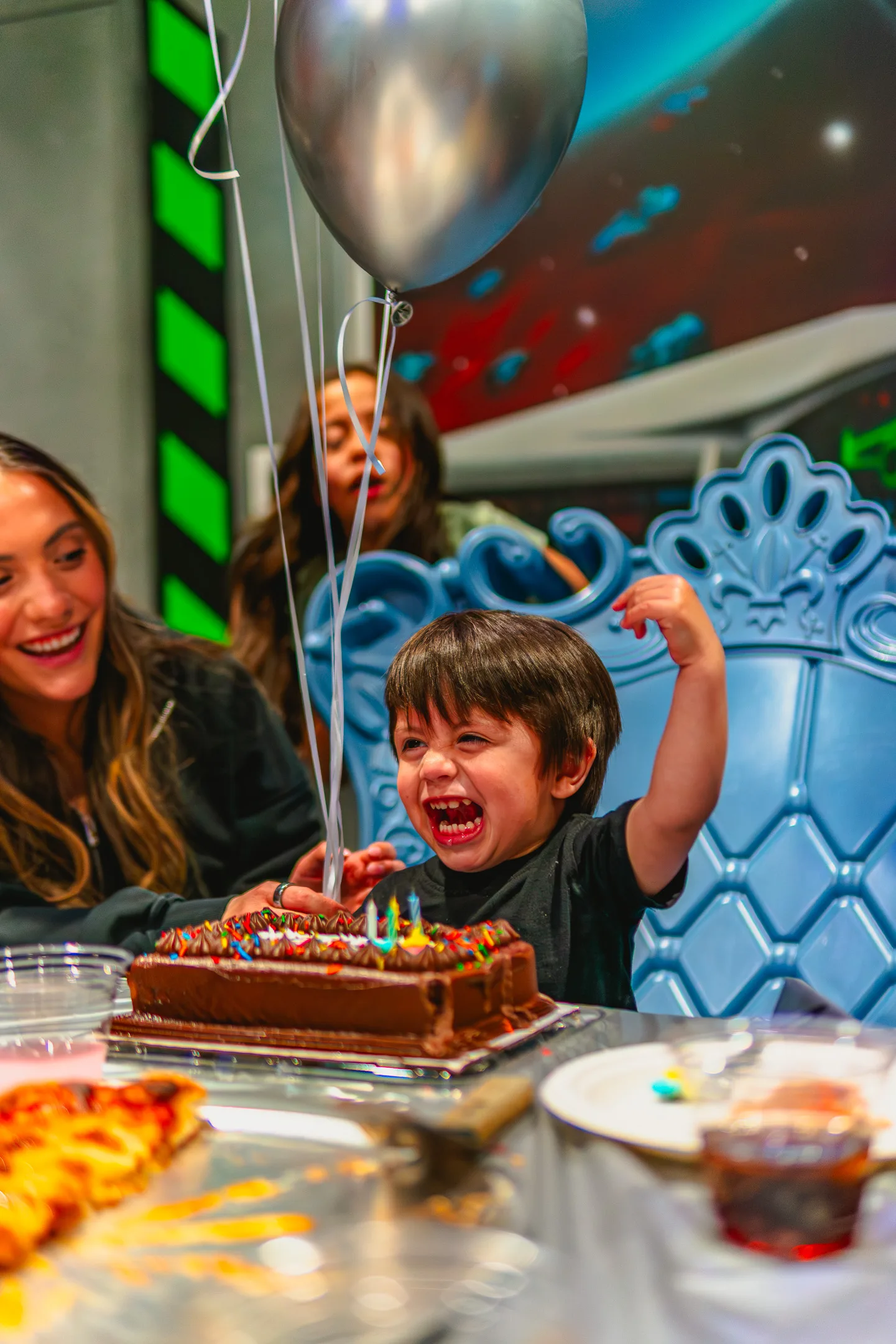A birthday kid celebrating with a cake and balloons in a themed party room